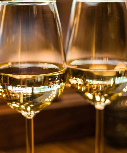 Two elegant wine glasses filled with white wine, captured with a beautiful bokeh effect.